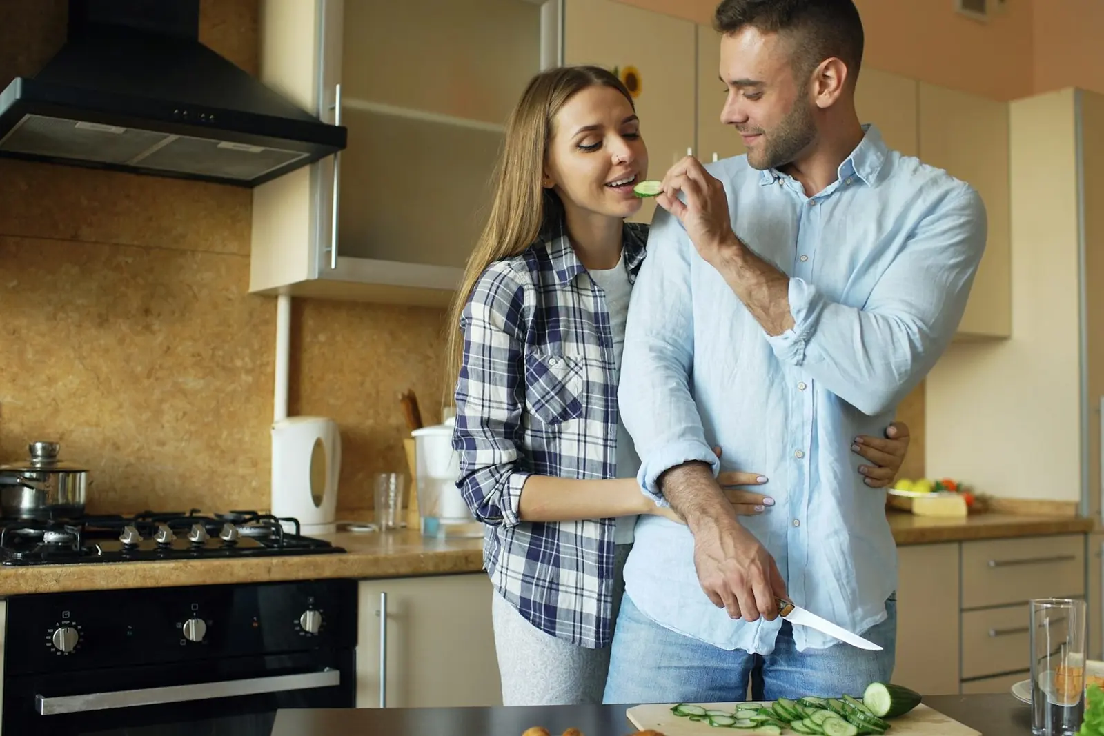 Casal a cozinhar junto e a partilhar uma prova na cozinha.